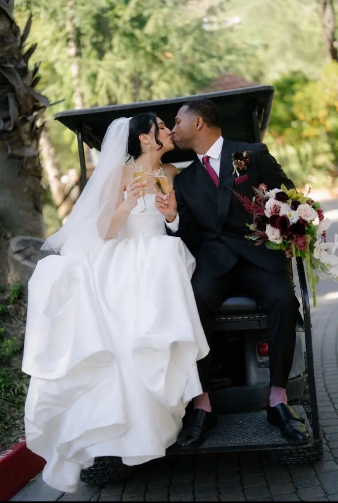 Bride and groom kissing in a golf cart with champagne flutes