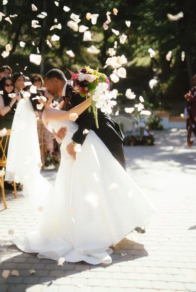 Bride and groom kissing under a shower of rose petals